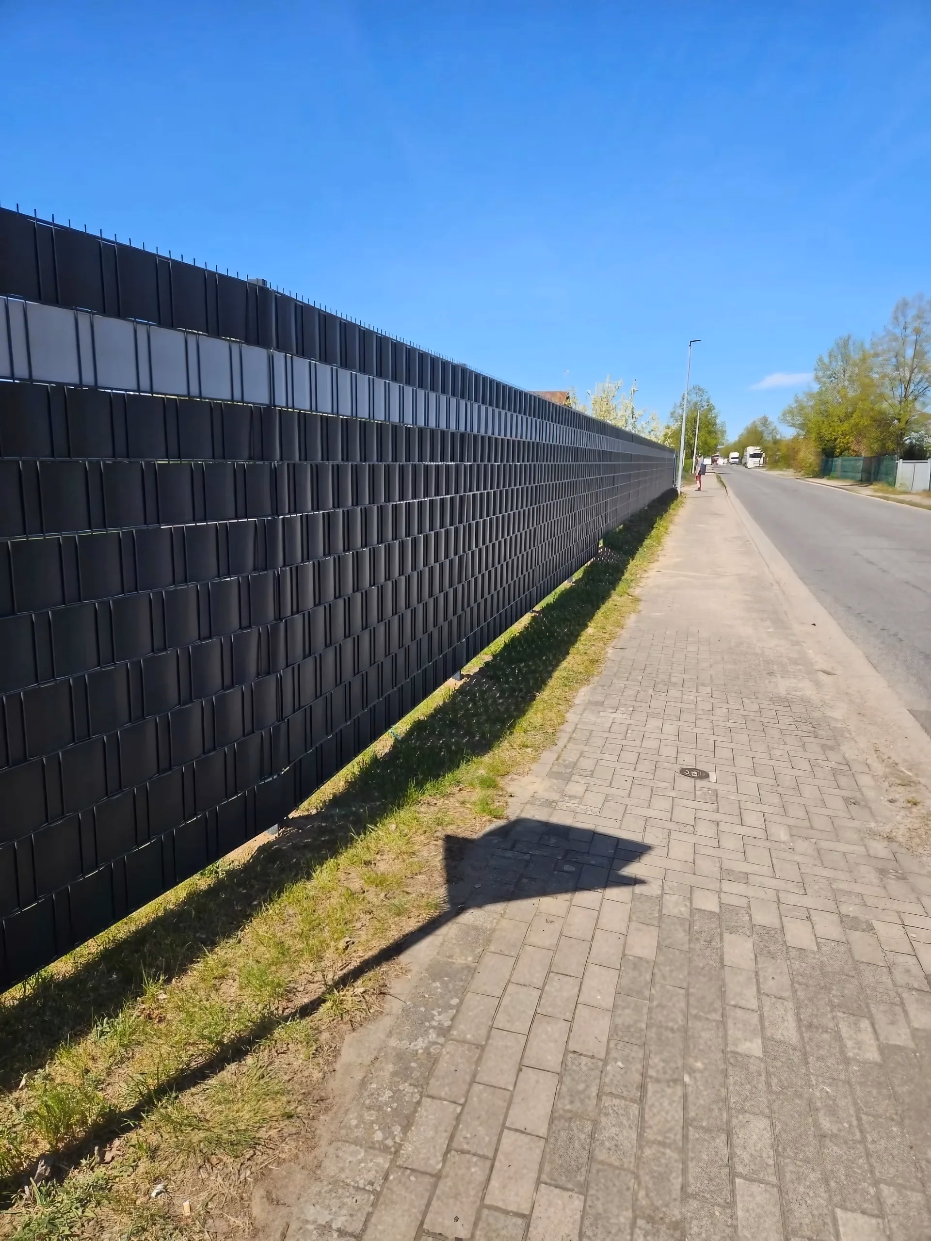 Langer Doppelstabmattenzaun in Anthrazit mit Sichtschutzstreifen entlang der Straße als Grundstücksgrenze