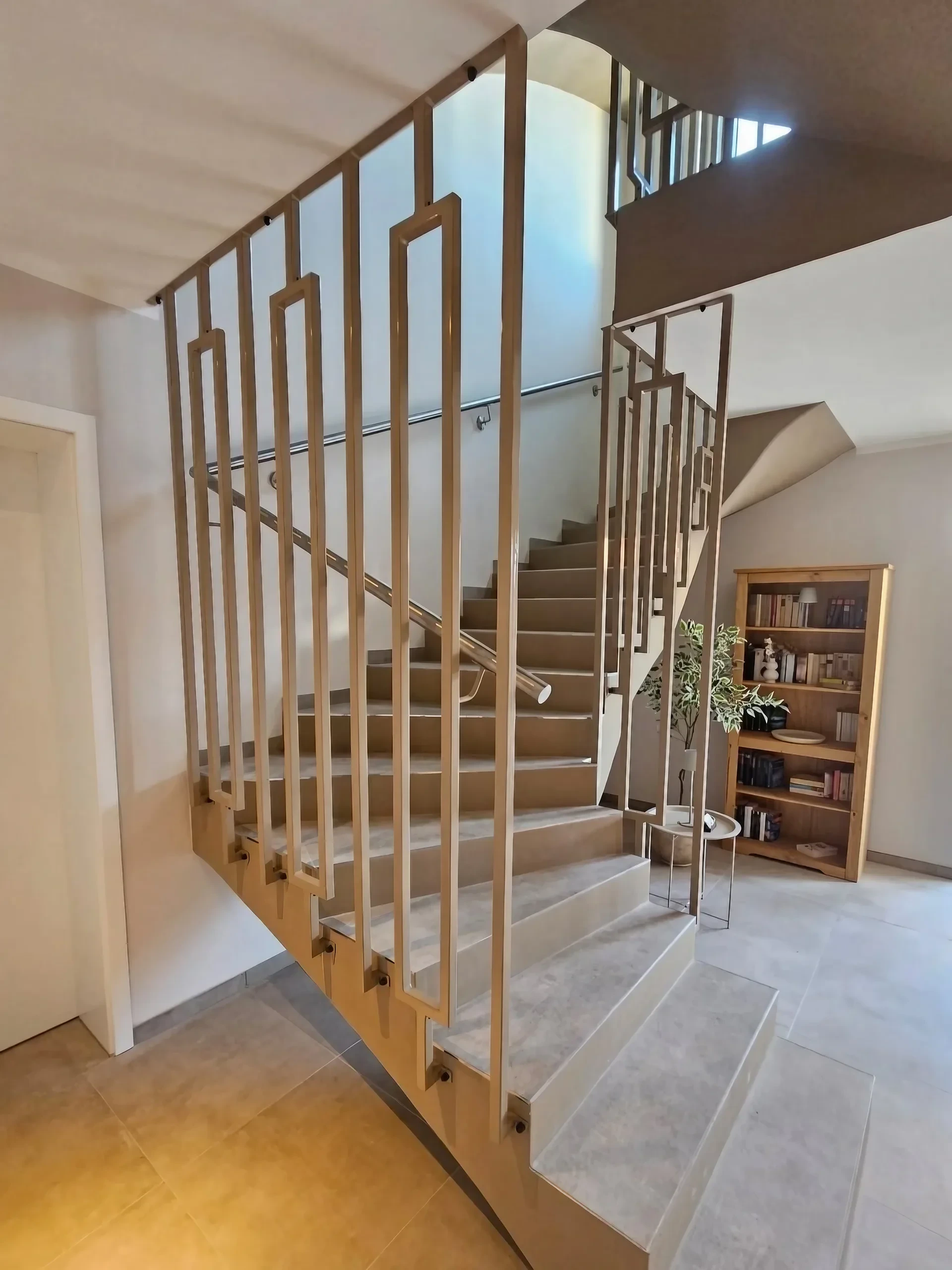Treppengeländer aus Stahl mit dekorativer Rahmenfüllung in Champagner und Edelstahl-Handlauf im modernen Treppenhaus